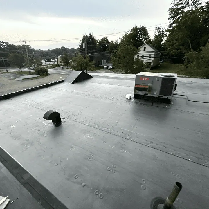 Black rubber EPDM flat roof around a rooftop HVAC unit and vents