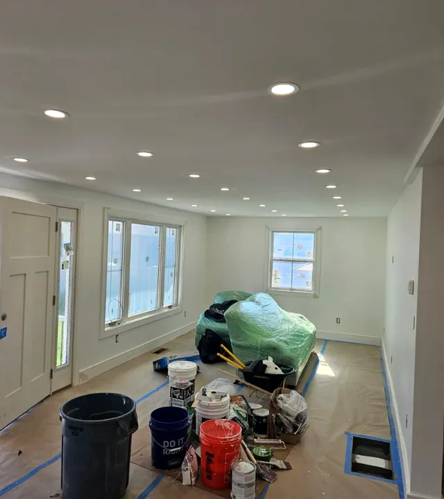 Long finished room with smooth walls, recessed lights and new windows, floor still protected