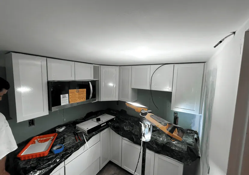 White kitchen cabinets installed and counters being fitted, mid-remodel