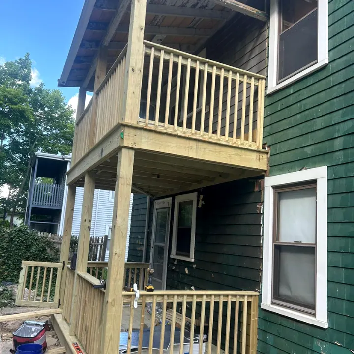 New wood porch railings and balusters against dark green siding