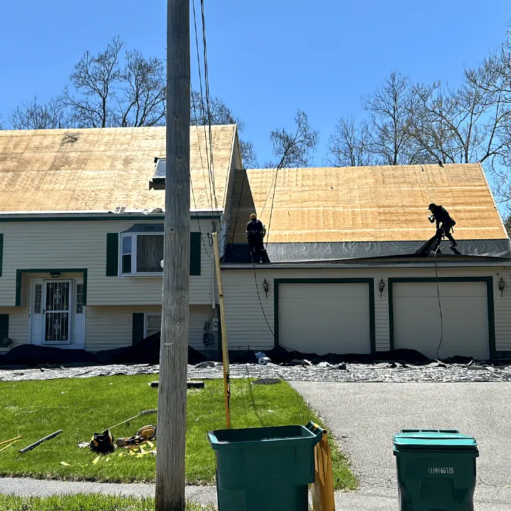 Roofers laying new sheathing on a house and attached garage roof