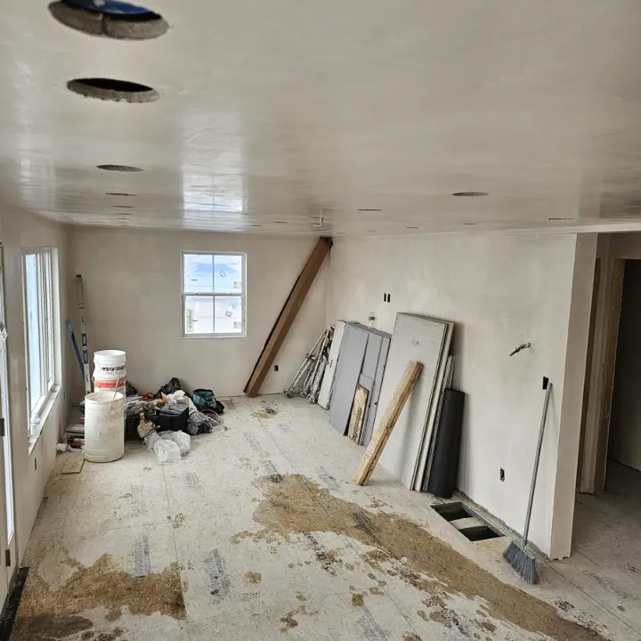 Room stripped to the subfloor with new walls up, materials stacked, before finishes