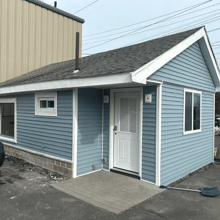 The same building with new blue vinyl siding, white trim and a new white door