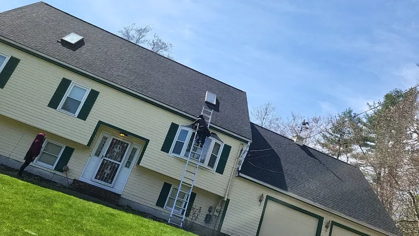 Side of a colonial with new tan vinyl siding and a white columned porch